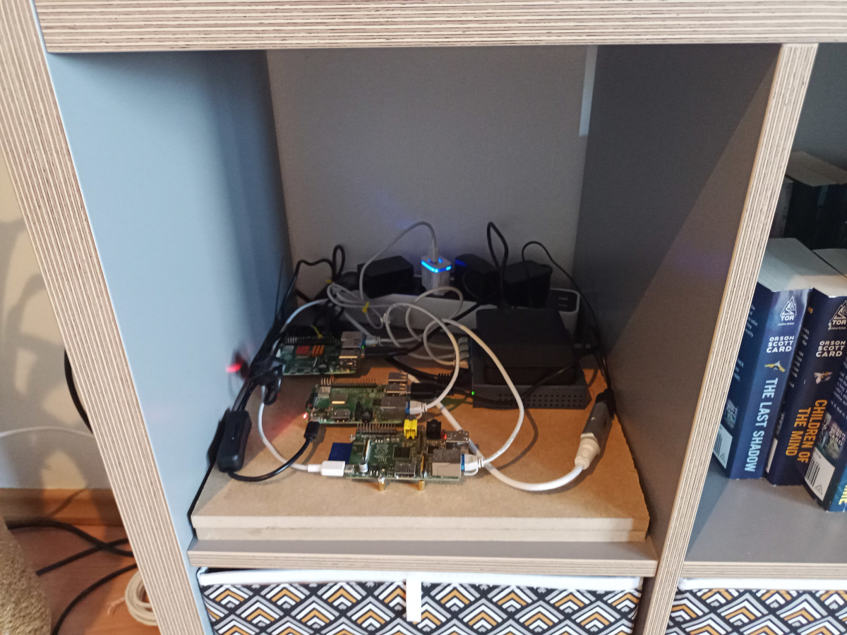 raspberry pis, switch, and external harddrive on wood plank sitting in bookshelf
