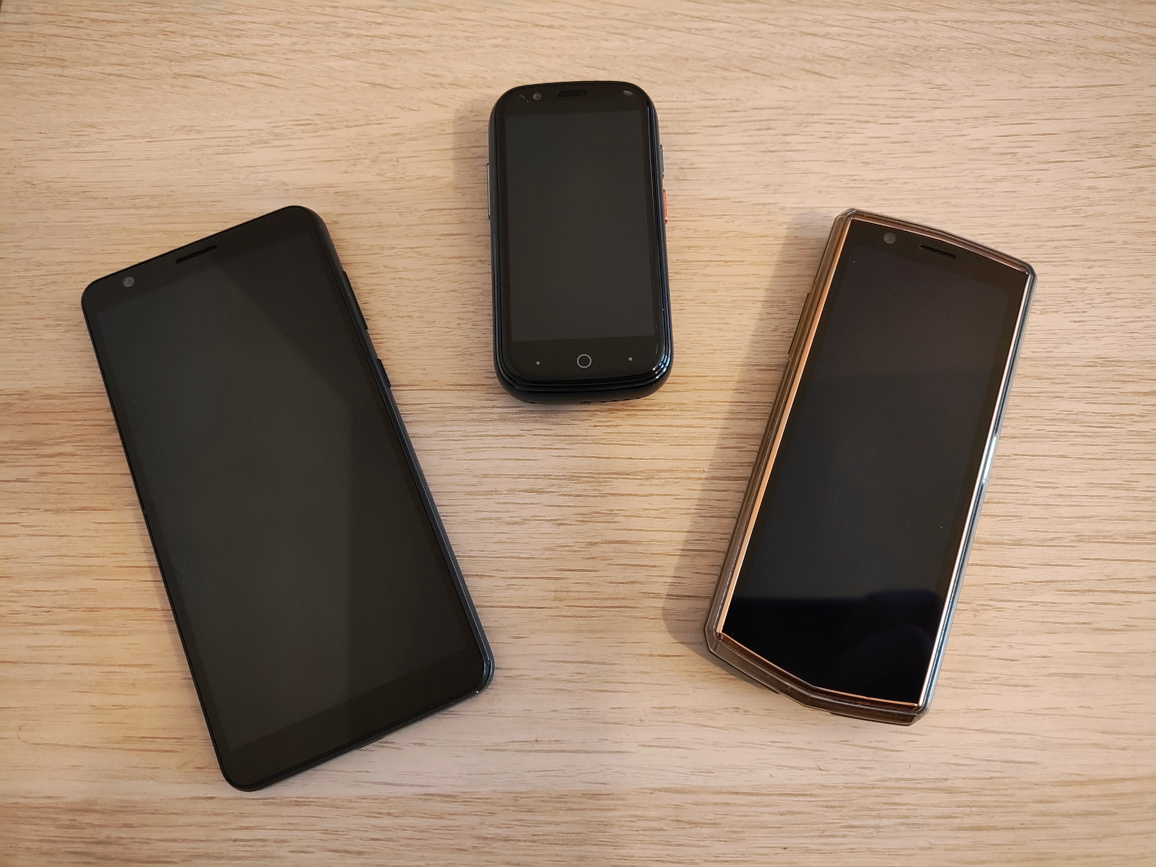 Three of my older phones laid on my wooden desk
