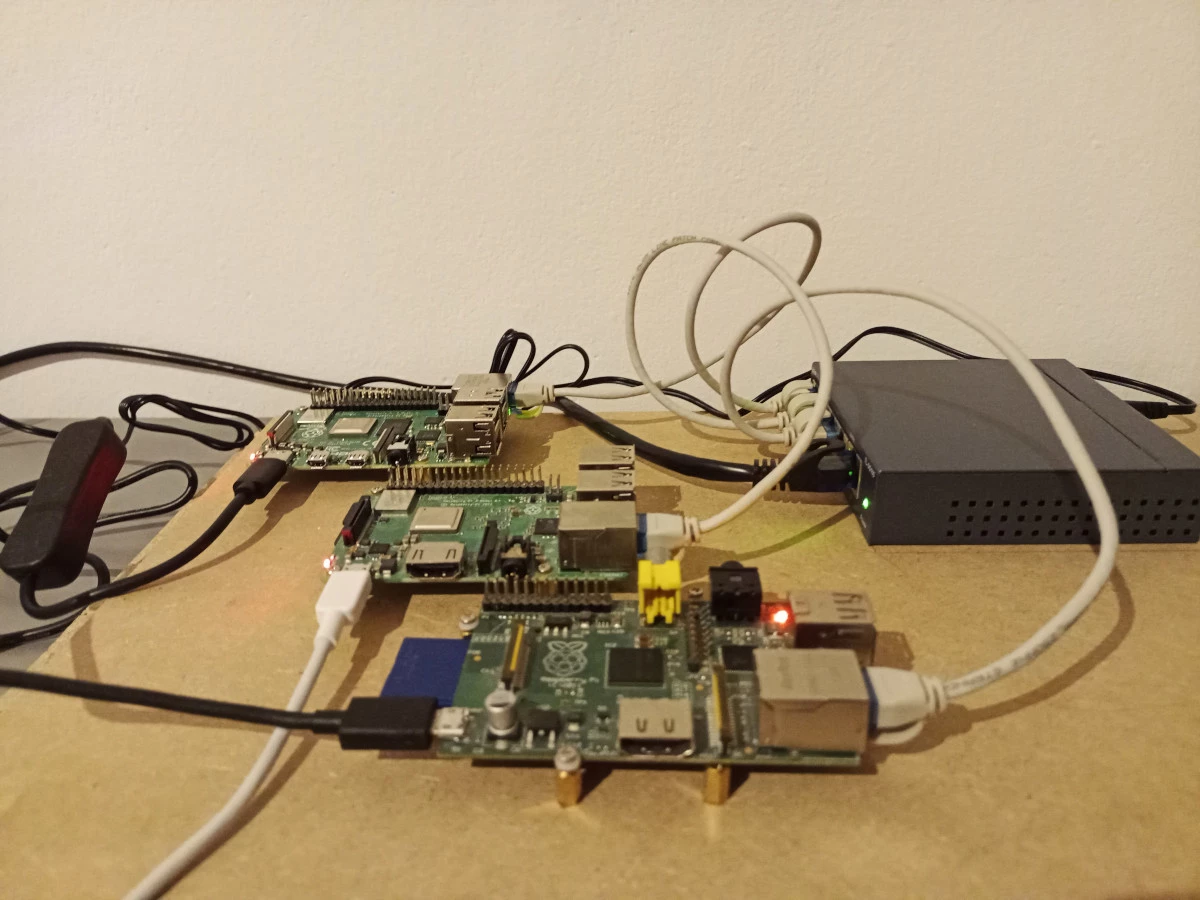3 raspberry pis mounted on screws on wood and connected to a network switch